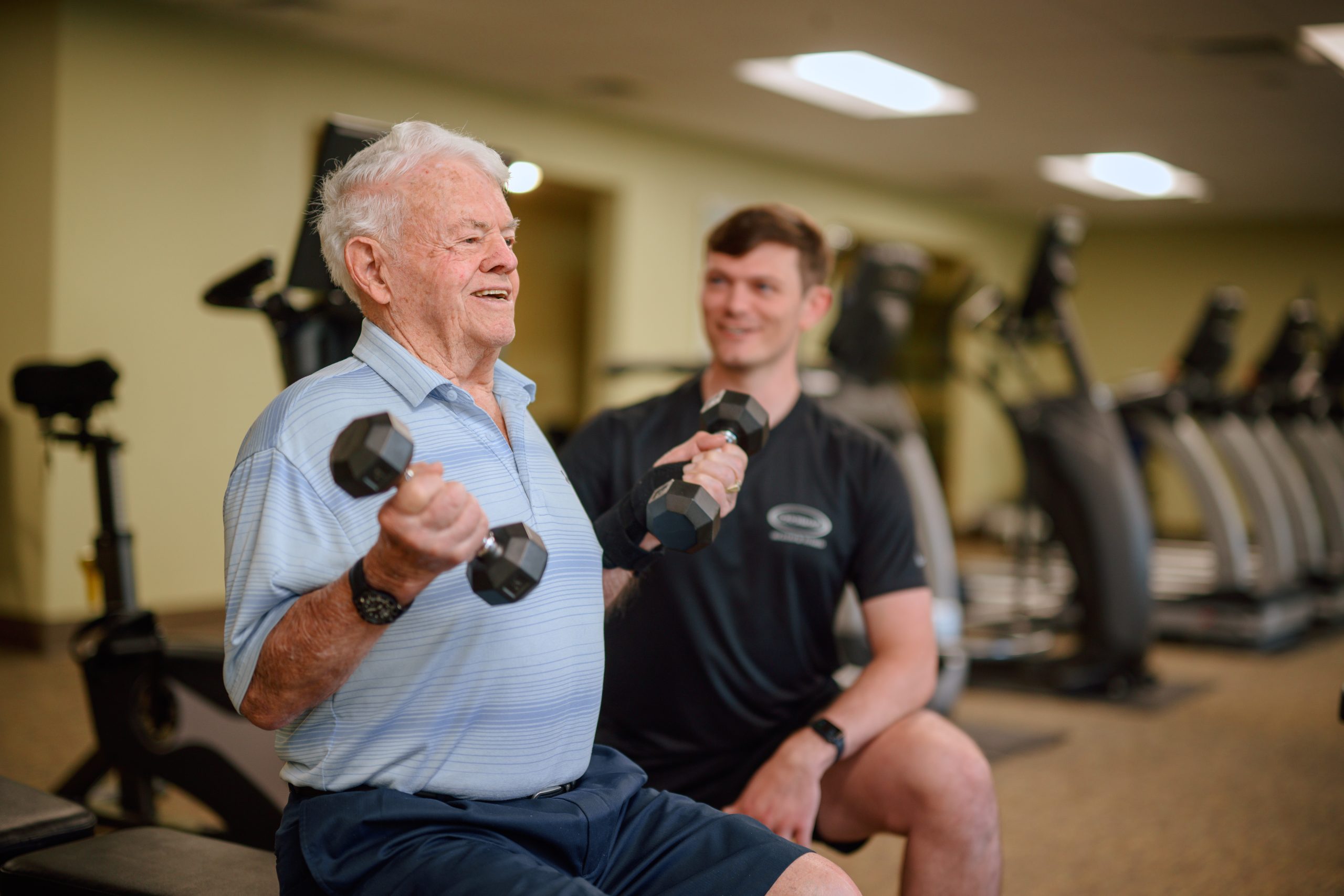 Resident lifting weights under supervision of team member